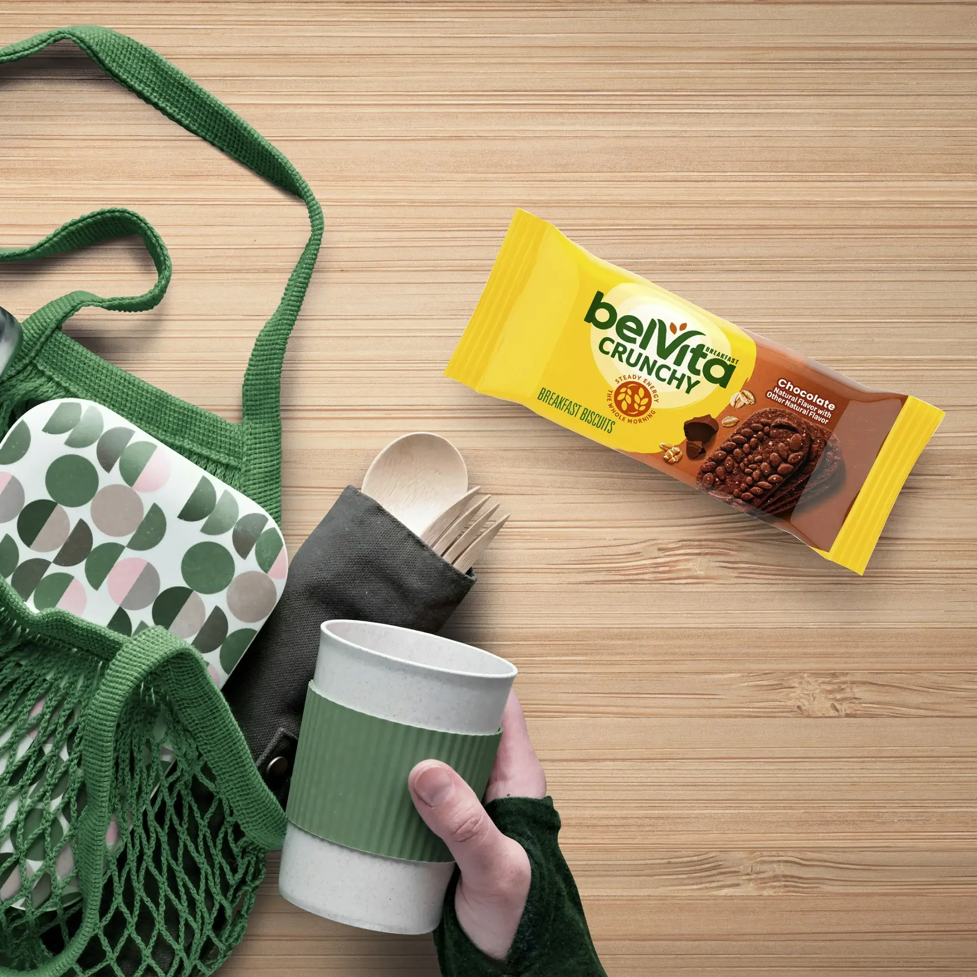 belVita Crunchy breakfast biscuits on a table with eco-friendly utensils and a green bag.